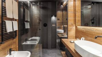 A modern bathroom with a glass-enclosed shower, a wooden vanity, and a large sink.