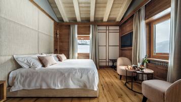 Un dormitorio con una cama grande, suelo de madera, una mesita con una planta y una silla.