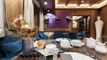 Una mesa de comedor dispuesta con vajilla blanca, un florero con flores secas y un vaso de vidrio transparente.