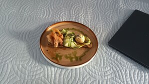 En tallrik med mat står på ett sängbord med ett vadderat överdrag, och bredvid ligger en svart anteckningsbok.