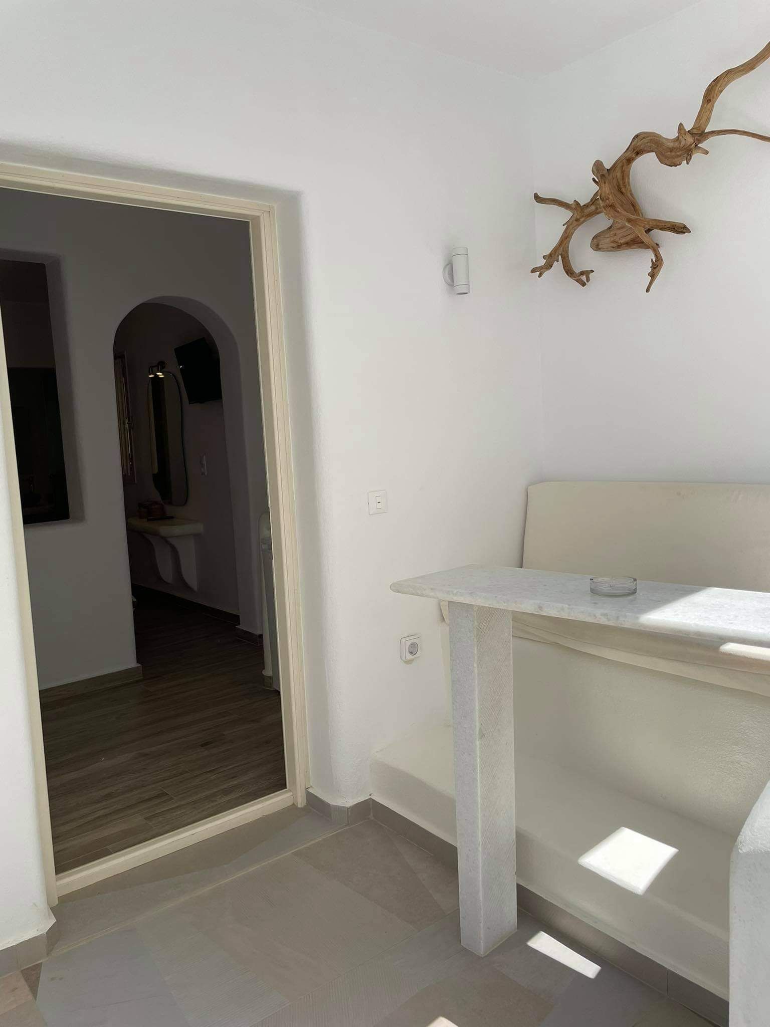 A modern interior with a white wall, a wooden branch decoration, and a small table.