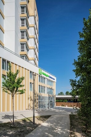 A modern hotel building with a clear sky, a well-maintained lawn, and a pathway leading to the entrance. - Holiday Inn Express & Suites Reims - Rives de Vesle (Reims)