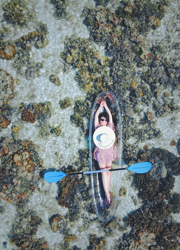 Una persona en kayak sobre una playa rocosa con agua cristalina.
