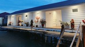 A waterfront property with a dock extending into the water, a covered walkway, and potted plants along the side. - Bubblefish water villa (Semporna)