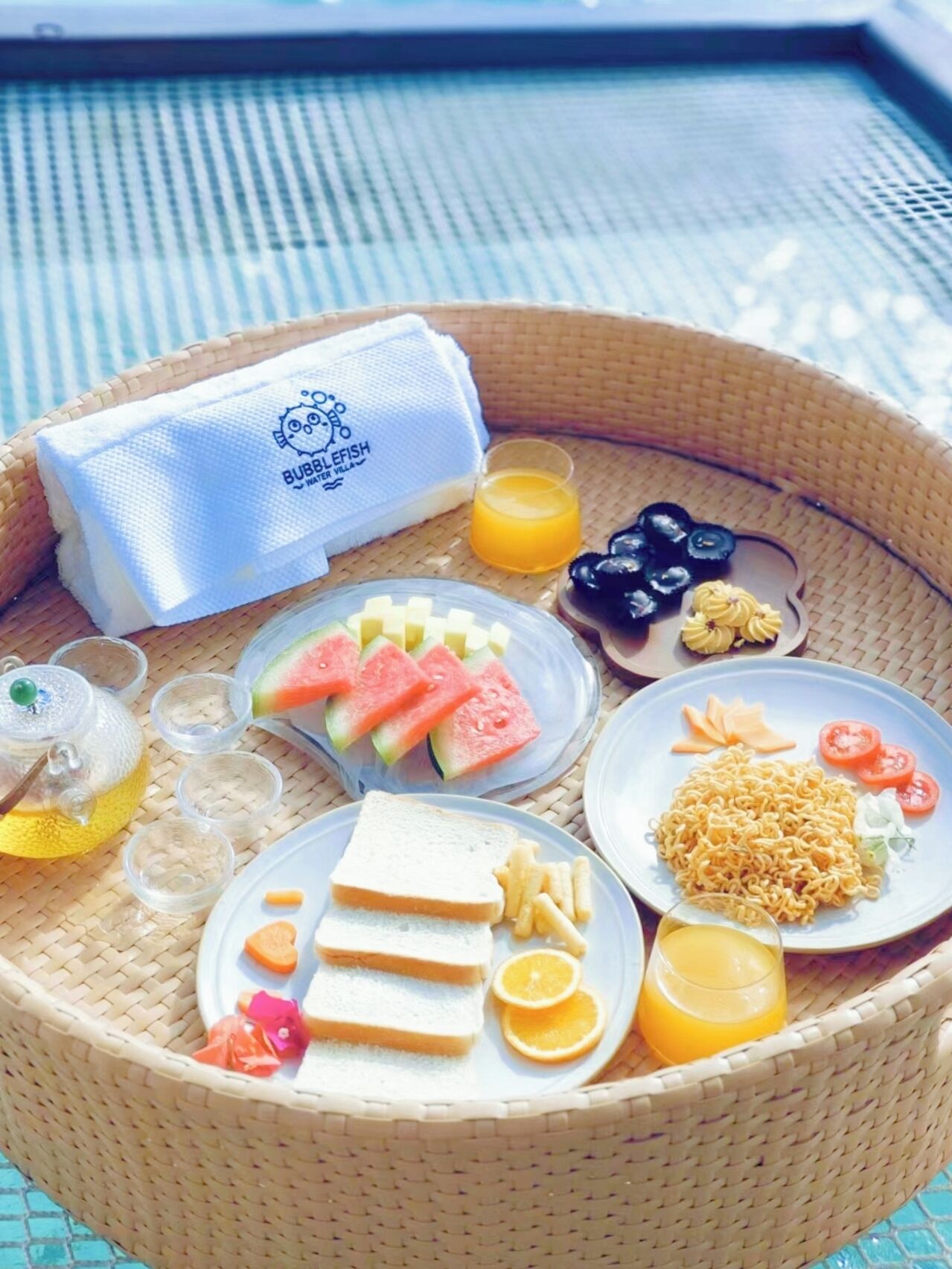 A breakfast tray with various foods and drinks, including toast, fruit, and a bottle of orange juice.