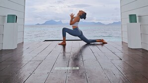 A person performing a yoga pose on a wooden deck with a view of the sea and mountains. - Bubblefish water villa (Semporna)