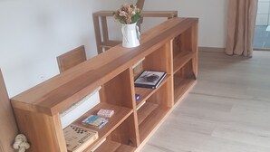 Een houten boekenkast met een bloevas, een boek en een schaakspel.