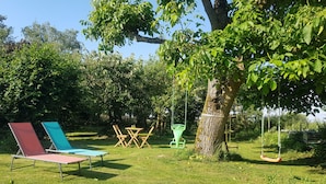 Een gazon met een schommel, een picknicktafel en twee comfortstoelen.