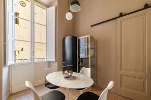A room with a round table, chairs, a black cabinet, a glass cabinet, and a sliding door.