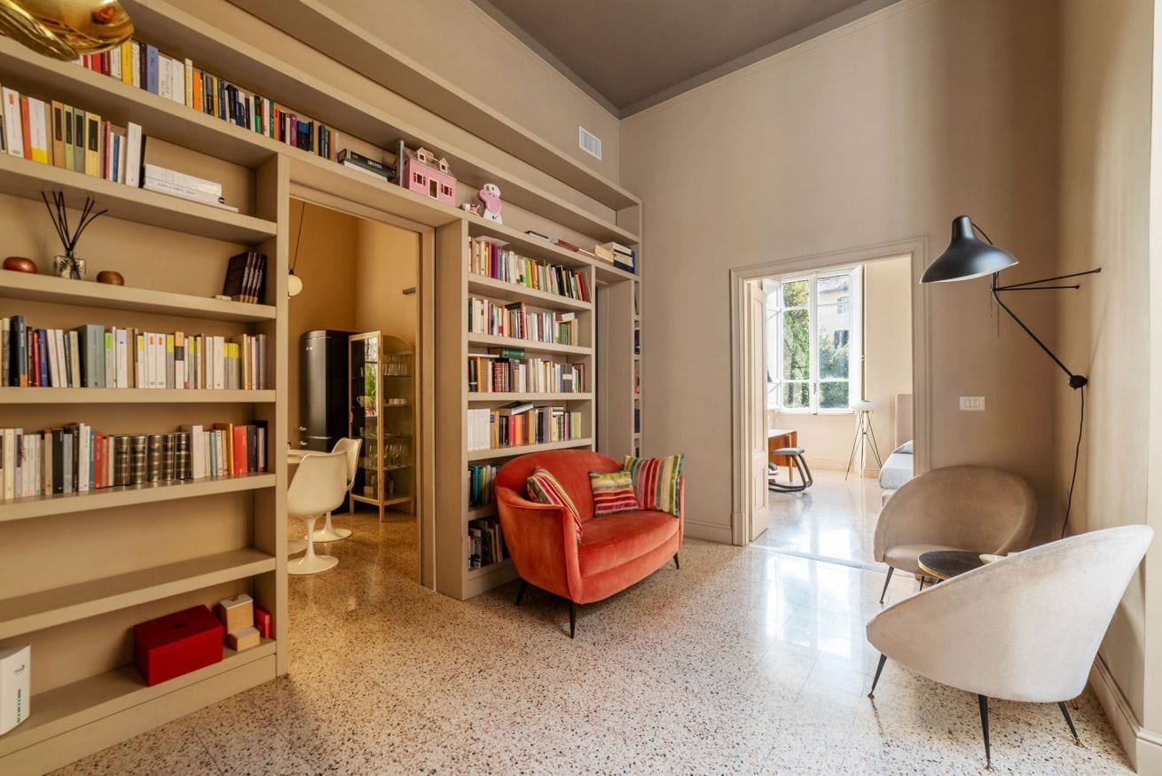 Une pièce spacieuse avec une grande bibliothèque, un canapé rouge et un fauteuil moderne.