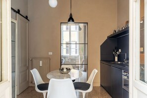 Eine kompakte Küche mit Essbereich, einem großen Fenster und einer Hängelampe.