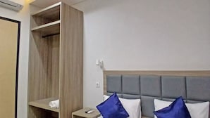 Une chambre d’hôtel avec un lit, une table de chevet, une armoire en bois et un luminaire au plafond.