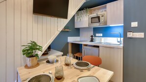 Cocina compacta con microondas, fregadero y un pequeño comedor con una mesa para dos.