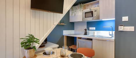 Cocina compacta con microondas, fregadero y un pequeño comedor con una mesa para dos.