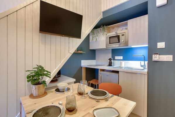 A compact kitchen with a microwave, sink, and a small dining area with a table set for two.