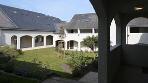 Un patio con un edificio que presenta varios arcos y un techo inclinado.