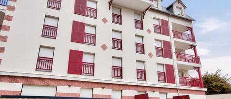 A multi-story building with a stone base and red balconies.