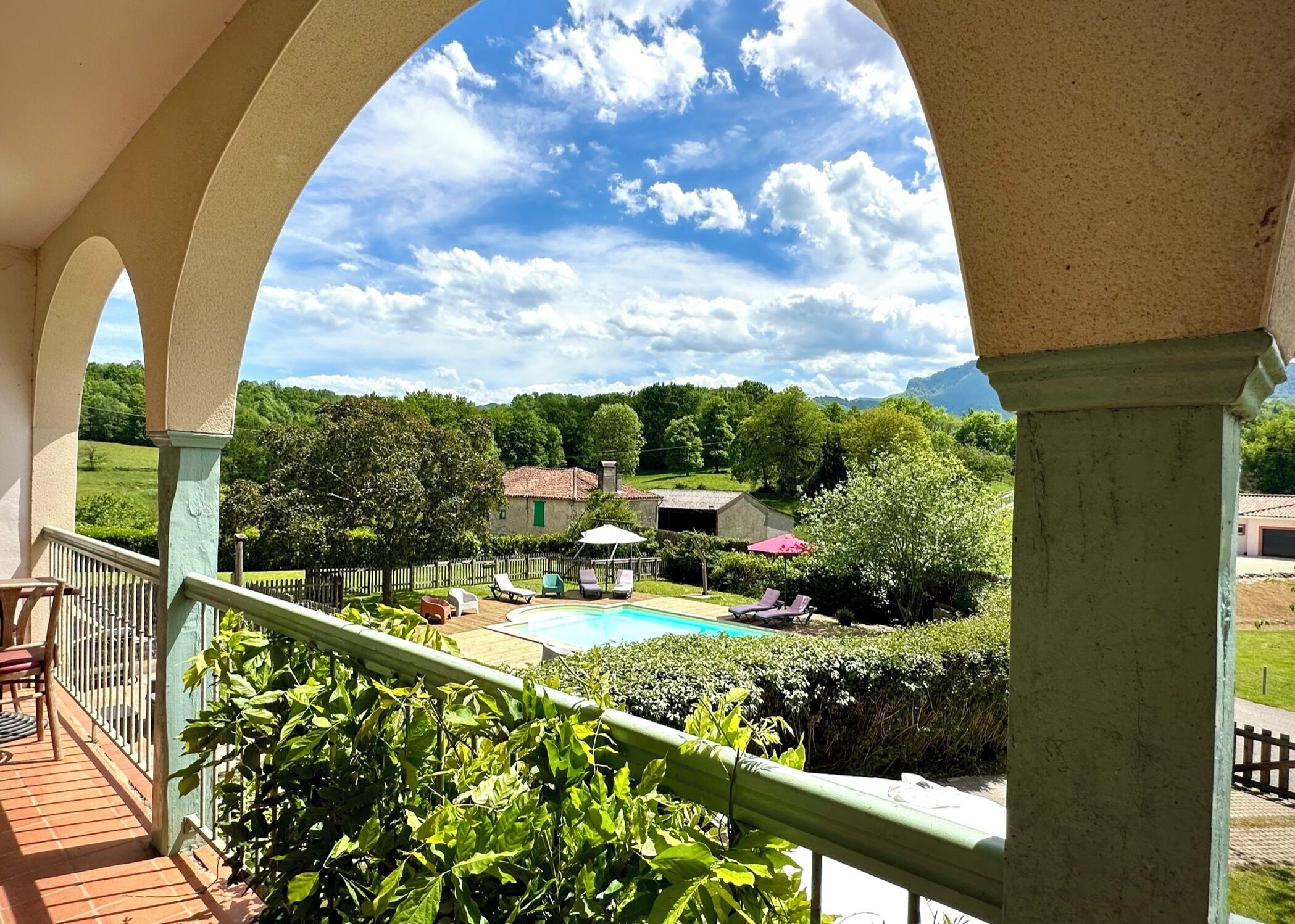 Ein Poolbereich mit Blick auf ein Haus und umliegendes Grün.