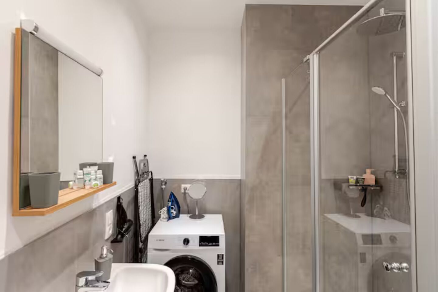 Une salle de bain moderne avec une douche à parois de verre, un lave-linge encastré et un miroir au-dessus du lavabo.