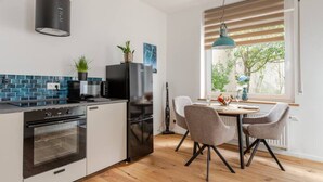 A modern kitchen with a built-in oven, a black refrigerator, and a dining area with a table and chairs.