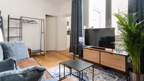 A modern living room with a sofa, a coffee table, a TV, and a plant.