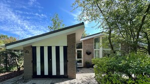 Ein modernes Haus mit Kiesauffahrt, einem schwarz-weißen Tor und einer Ziegel-Fassade.