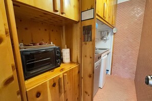 A compact kitchen with a microwave, wooden cabinets, and a small sink. - Family Chalet in Pila, Comfort and Fun (Pila)