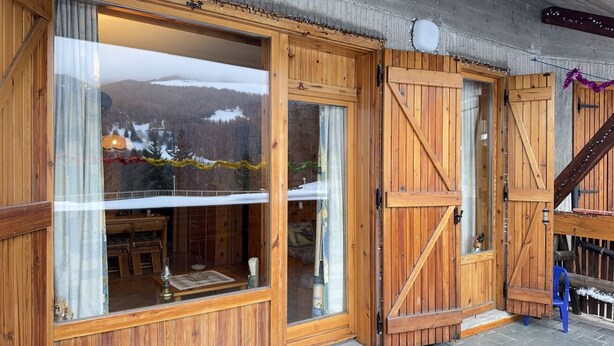 Eine Holzhütte mit großen Fenstern, einer Tür und einer Treppe.