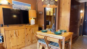 Ein Holztisch mit Stühlen, einem Fernseher und einer Lampe.