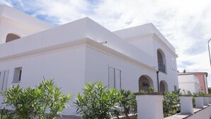 A white building with a flat roof and arched windows. - Cosy apartment for 4 people with pool, WIFI, A/C and TV (Orosei)
