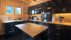 A modern kitchen with wooden cabinetry, a central island, and a window with a view of greenery.