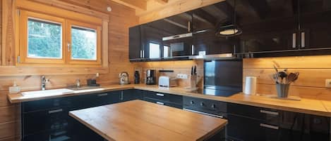 A modern kitchen with wooden cabinetry, a central island, and a window with a view of greenery.