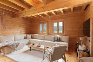 A log cabin interior with a sectional sofa, a wooden coffee table, and a television mounted on the wall. - Toison D'or - 8 pers. - Jacuzzi + sauna (Xonrupt-Longemer)