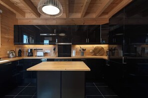 A modern kitchen with black cabinets, a wooden countertop, and a central island.