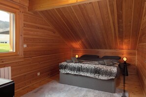 A bedroom with a sloped ceiling, a bed with a blanket, two bedside lamps, and a window. - Toison D'or - 8 pers. - Jacuzzi + sauna (Xonrupt-Longemer)