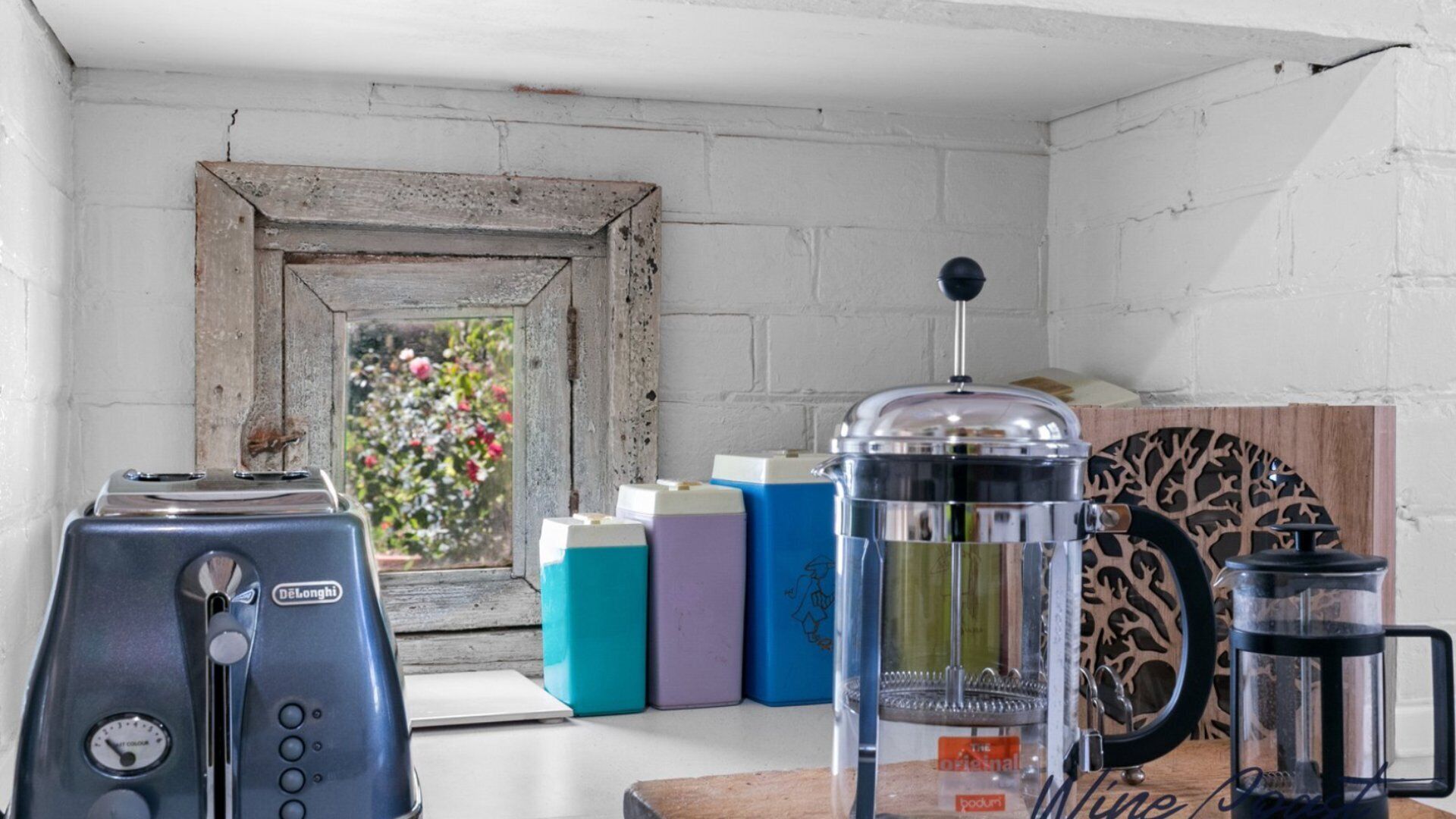 A kitchen with a coffee maker, a toaster, and colorful containers on the counter.