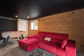 Ein Zimmer mit einem roten Sofa, einem Kicker und einer Holzwand.