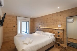 Ein modernes Schlafzimmer mit einer Holzverkleidung, einem Bett mit weißen Leinentüchern, einem Nachttisch mit einer Lampe und einem großen Spiegel.