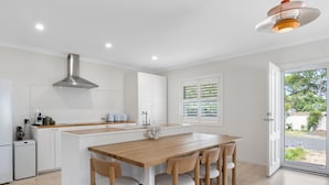 Una cocina moderna con armarios blancos, una mesa de comedor de madera y un horno empotrado.