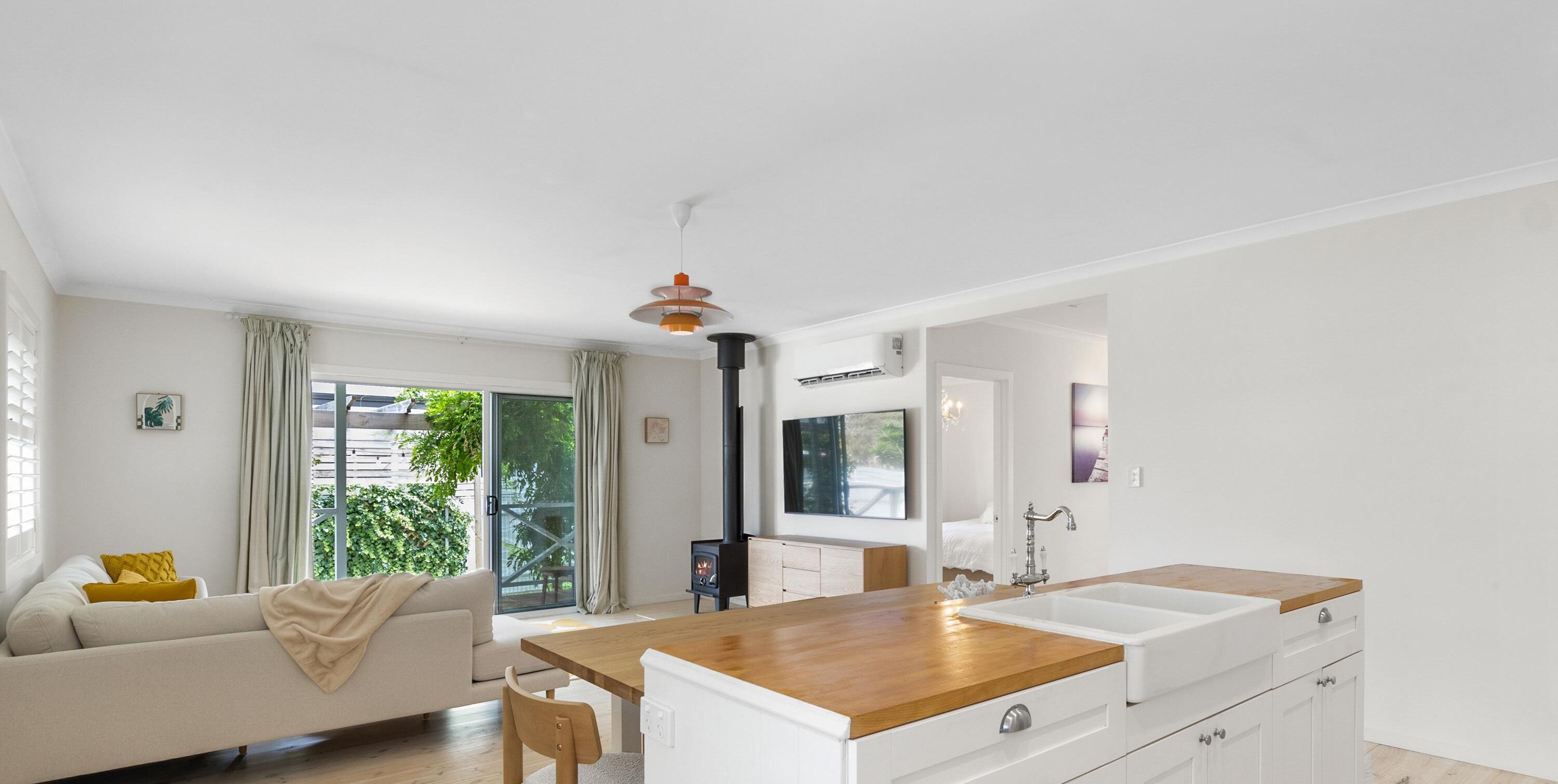 A modern kitchen with a wooden countertop, white cabinets, and a built-in stove.