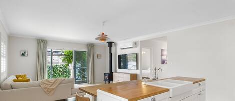 A modern kitchen with a wooden countertop, white cabinets, and a built-in stove.