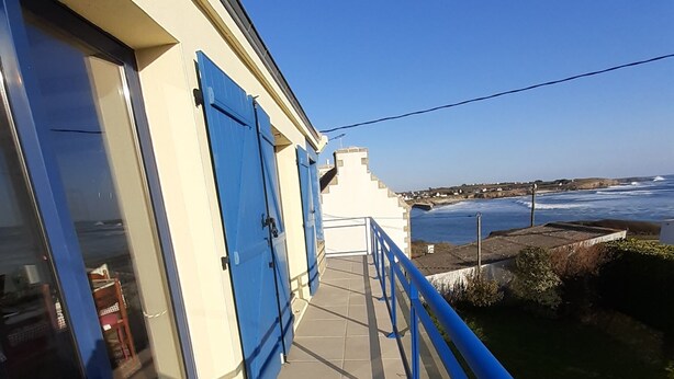 Un balcón con barandillas azules que da a la costa.