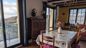 Un comedor con una mesa preparada para cuatro personas, un aparador de madera y vistas al exterior.