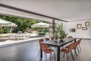 A spacious indoor area with a dining table, chairs, and umbrellas.