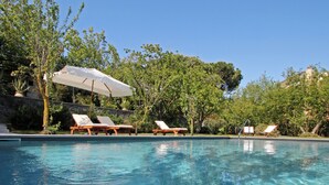 A clear swimming pool with lounge chairs and umbrellas.
