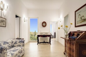 Un salón con sofá, una mesa de madera, un reloj y un cuadro en la pared.