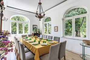 A dining room with a table set for six, large windows, and a chandelier.