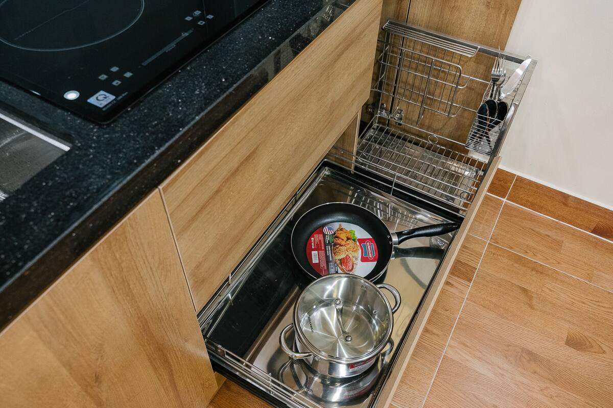 Cuina amb una placa d'inducció negra, una paella i una olla sobre un safata.