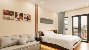 A modern hotel room with a bed, a sofa, and artwork on the wall.