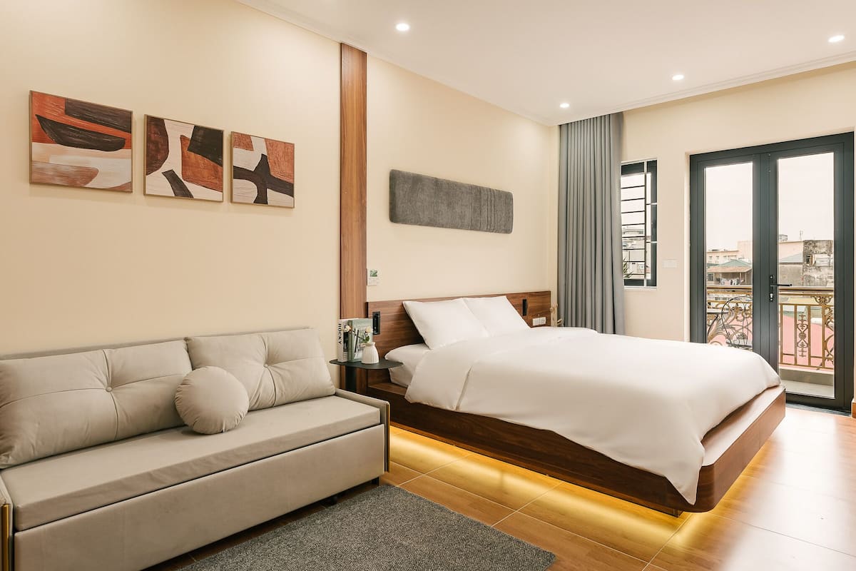 Habitació d'hotel moderna amb un llit, un sofà i obra d'art a la paret.